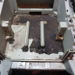 Plastikowe wnętrze urządzenia z widocznym brudem i osadem.