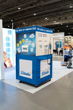 Blue and white Eltako trade show booth with “THE HOME OF INNOVATION” banner