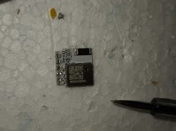 Small electronic module with QR code on white surface with screwdriver tip nearby