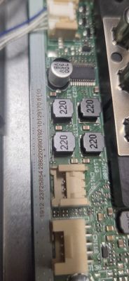 Zbliżenie na płytkę drukowaną z elementami elektronicznymi, w tym cewki 220 i kondensator 100 µF 35V.