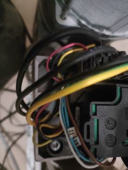 Zbliżenie na połączenie elektryczne w silniku trójfazowym, z widocznymi kolorowymi przewodami.