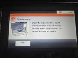 Ekran drukarki z komunikatem „Toner is empty” i instrukcją wymiany pojemnika z tonerem