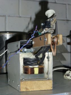 Homemade Welder on a Wooden Base Homemade welder with metal components and a wooden base.