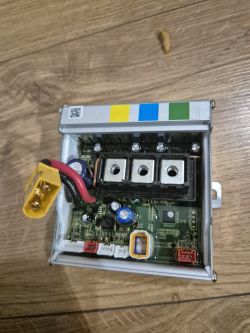 Zdjęcie sterownika urządzenia elektronicznego na drewnianej podłodze.