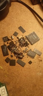 Rozsypane układy scalone i drobne elementy SMD na blacie, m.in. większy chip z napisem Agilent