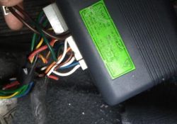 Naklejka na centrali alarmowej z widocznymi kolorowymi przewodami i złączami.