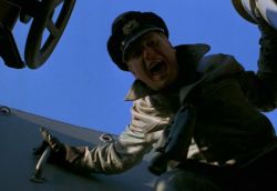 Mężczyzna w mundurze marynarza spogląda w dół, krzycząc.