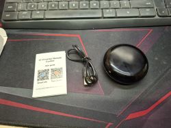 Black, round Tuya Wi-Fi IR transmitter on a white background.