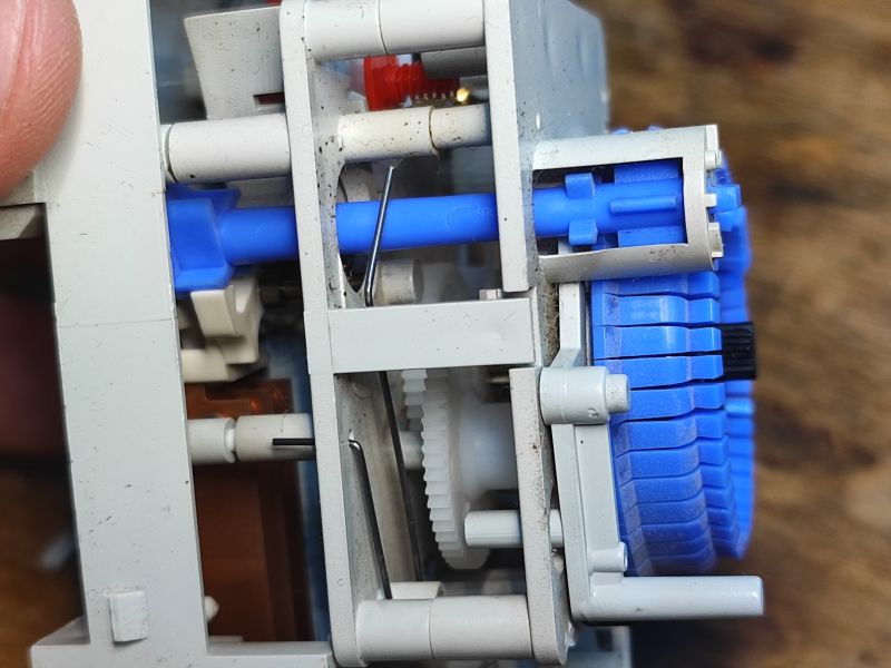 Wnętrze mechanicznego programatora czasowego z widocznymi zębatkami.
