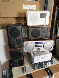 Stos radioodbiorników marki Audizio na półce, wraz z innymi pudełkami elektronicznymi.