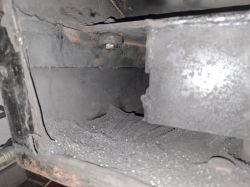 Wnętrze pieca z widoczną powierzchnią pokrytą popiołem i metalowymi elementami