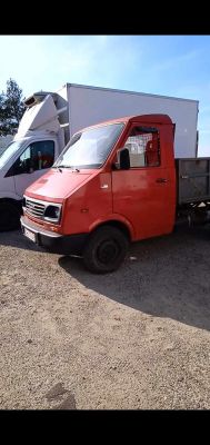 Czerwony samochód dostawczy zaparkowany obok białej ciężarówki.