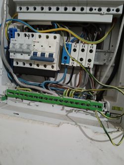 Zdjęcie wnętrza rozdzielnicy elektrycznej z przewodami i bezpiecznikami.