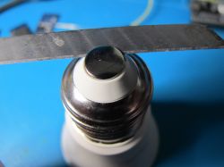 A light bulb shown in close-up, held in a vise.