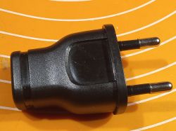Czarna wtyczka zasilająca z wbudowaną ładowarką USB na pomarańczowym tle