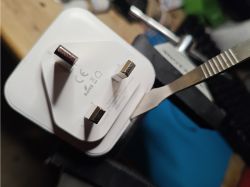Opening a Smart Electrical Plug Image of a three-pin electrical plug placed in a vise, partially opened with a tool.