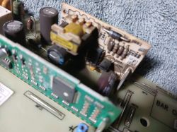 Zbliżenie na płytkę drukowaną z elementami elektronicznymi, w tym kondensatorami i transformatorem