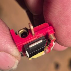 Close-up of a damaged electronic component Close-up of a red electronic component held between fingers