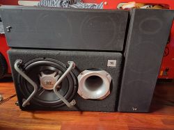 Voice Kraft and JBL speakers placed side by side on a wooden floor.