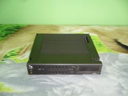 Black retro Schneider tuner lying on a carpet, with control panels in the front and a DCS connector on top.