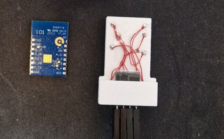 WBR3 module next to a programmer adapter with red wires and pogo pins in a white housing