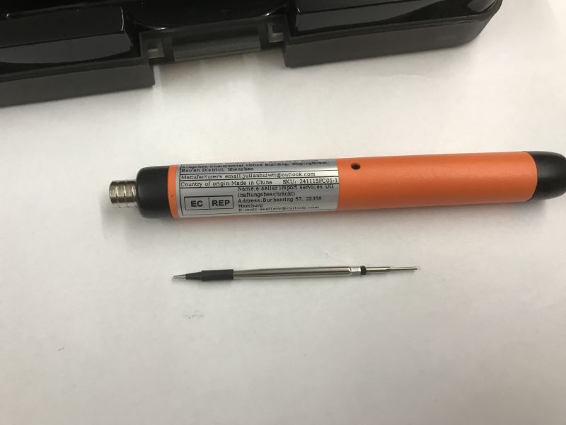 Orange USB soldering iron with a detached tip lying on a white surface