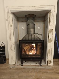 Fireplace under renovation with burning wood, surrounded by Varmsen/Skamol panels.