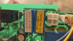 Close-up of relays on a green PCB in a Daewoo DWD-M1031 washing machine. The relays have white and yellow labels with markings.