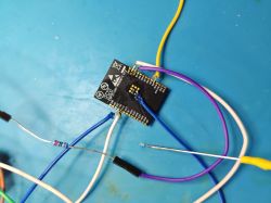 ESP32-C6 module connected to colored jumper wires on a blue work mat.