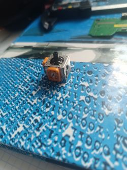 Analogowy drążek kontrolera DualShock 3 na tle niebieskiego wzoru.