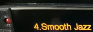 Close-up of a display showing yellow text “4. Smooth Jazz” next to a red button