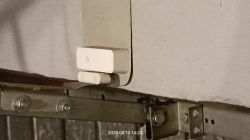 Kontaktron WiFi zamontowany na bramie garażowej, widoczna szyna i uchwyt metalowy