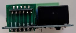 Close-up of a PCB with UART header pins and a black relay module on the right
