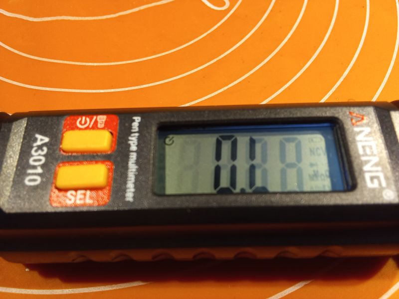 Cyfrowy miernik typu długopis Aneng A3010 na pomarańczowym tle.