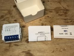 WSM16-W1 Wi-Fi switch module, manuals, and packaging on a wooden surface.