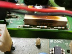 Bliska fotografia płytki elektronicznej z widocznymi rezystorami i przypalonym elementem.