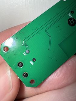 Close-up of a green circuit board with markings 24V and GND2 against a hand background.