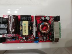 Czerwono-czarna płytka elektroniczna z widocznymi komponentami, w tym transformatorem i cewką.