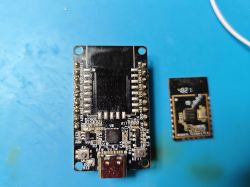 A PCB with a removed electronic module next to it, lying on a blue surface.