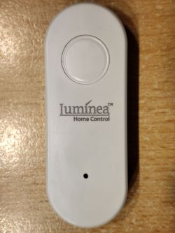 Luminea LED Controller White Luminea LED controller with logo on a wooden surface.