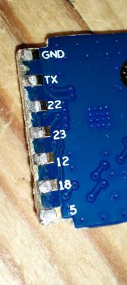 Fragment of a blue circuit board with visible contacts and labels.