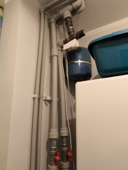 Instalacja zaworu mieszającego z pompą przy ogrzewaniu podłogowym Zawór mieszający i rury systemu ogrzewania z pompą i zasobnikiem w rogu pomieszczenia