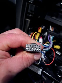 Osoba trzymająca kostkę elektryczną z przewodami w tle.