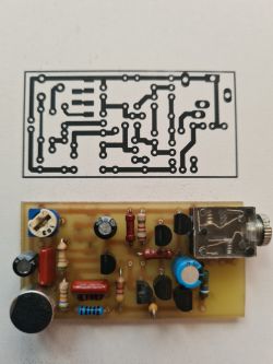 PCB with Components and Circuit Diagram PCB with mounted electronic components in front of a printed circuit diagram.