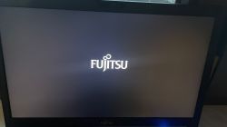 Logo Fujitsu na czarnym ekranie laptopa.