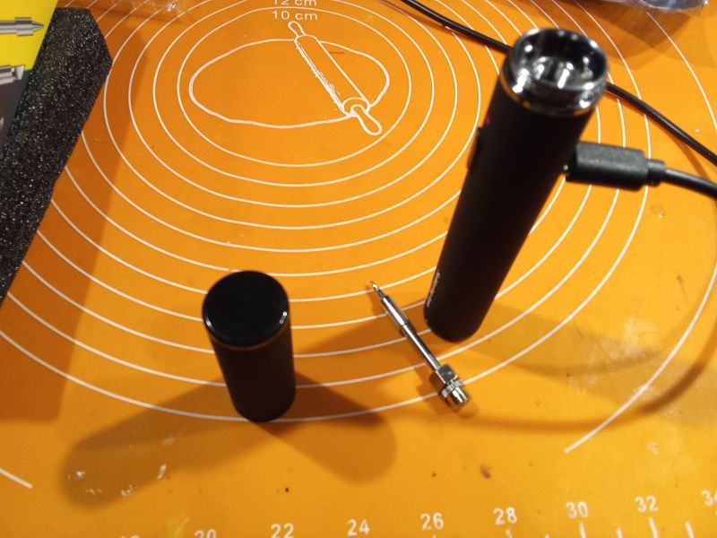 Przenośna lutownica z akumulatorem na okrągłej macie.