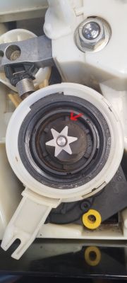 Zbliżenie mechanizmu z białym pierścieniem i metalową gwiazdką, zaznaczone czerwonym znacznikiem