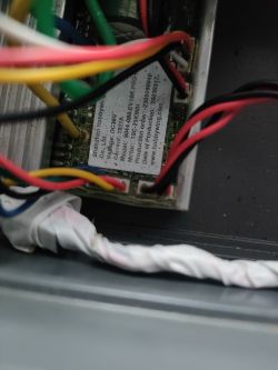 Zbliżenie na sterownik elektryczny z widocznymi kolorowymi przewodami i etykietą producenta.