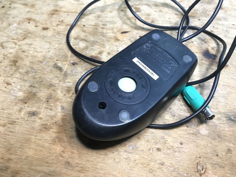 Back of a Ball Mouse with PS/2 Cable Back of an old ball mouse on a wooden table.