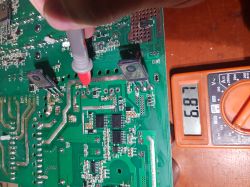 Multimeter measuring voltage on a PCB, displaying a reading of 6.87.